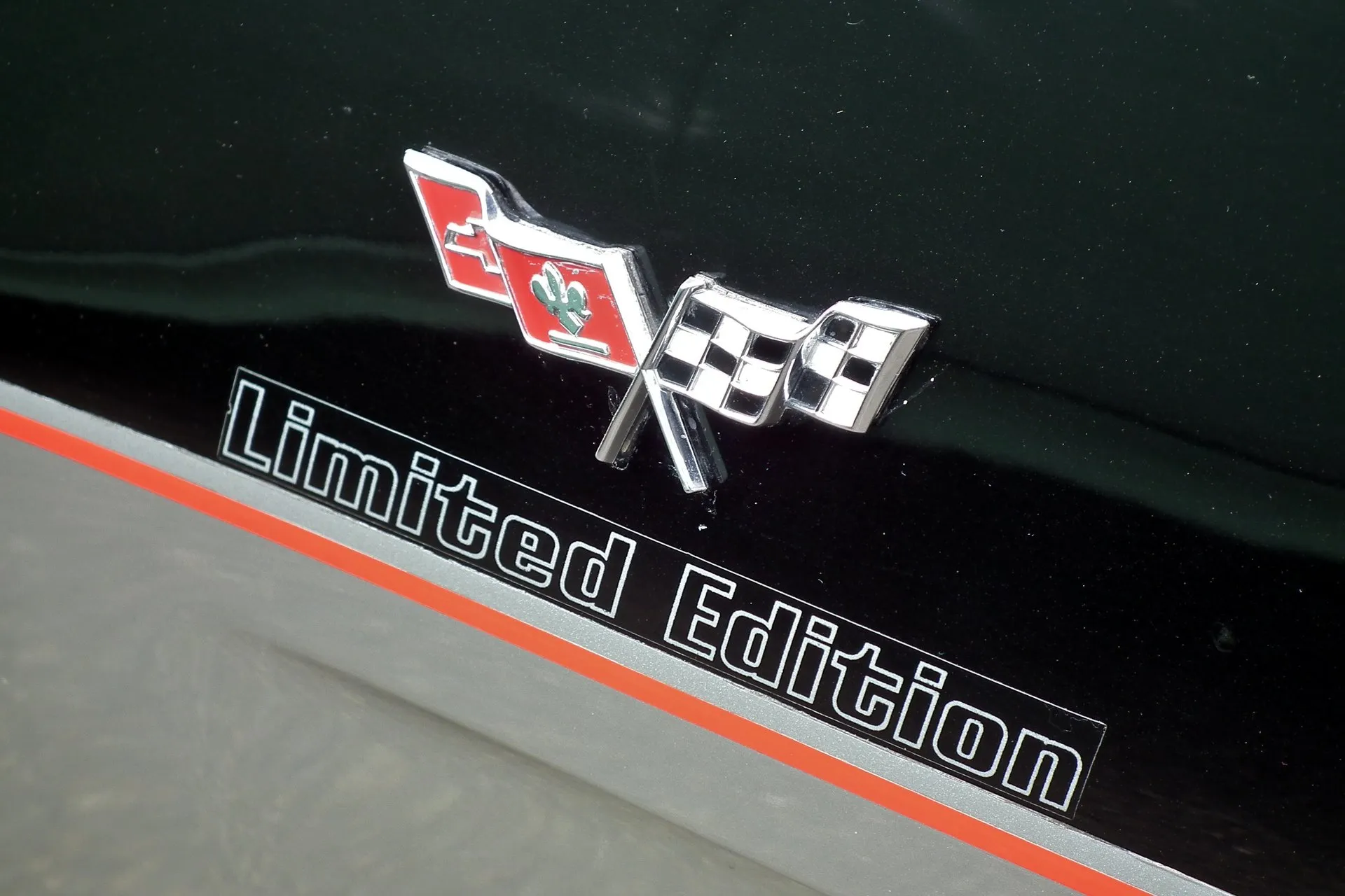 Close-up of a crossed-flags emblem above a Limited Edition decal on a black body panel, with a silver lower body and a red pinstripe below.