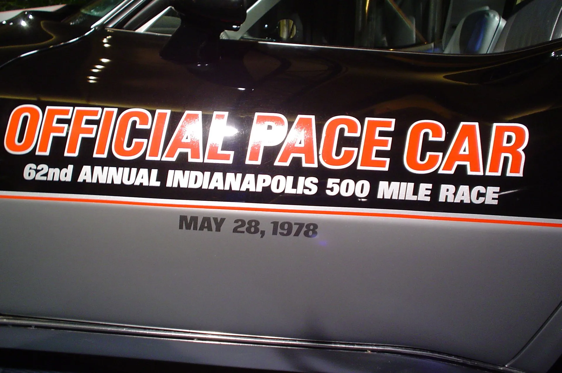 Lettering on the door of a black-over-silver Corvette reading Official Pace Car, 62nd Annual Indianapolis 500 Mile Race, May 28, 1978, with a silver seat visible through the window.
