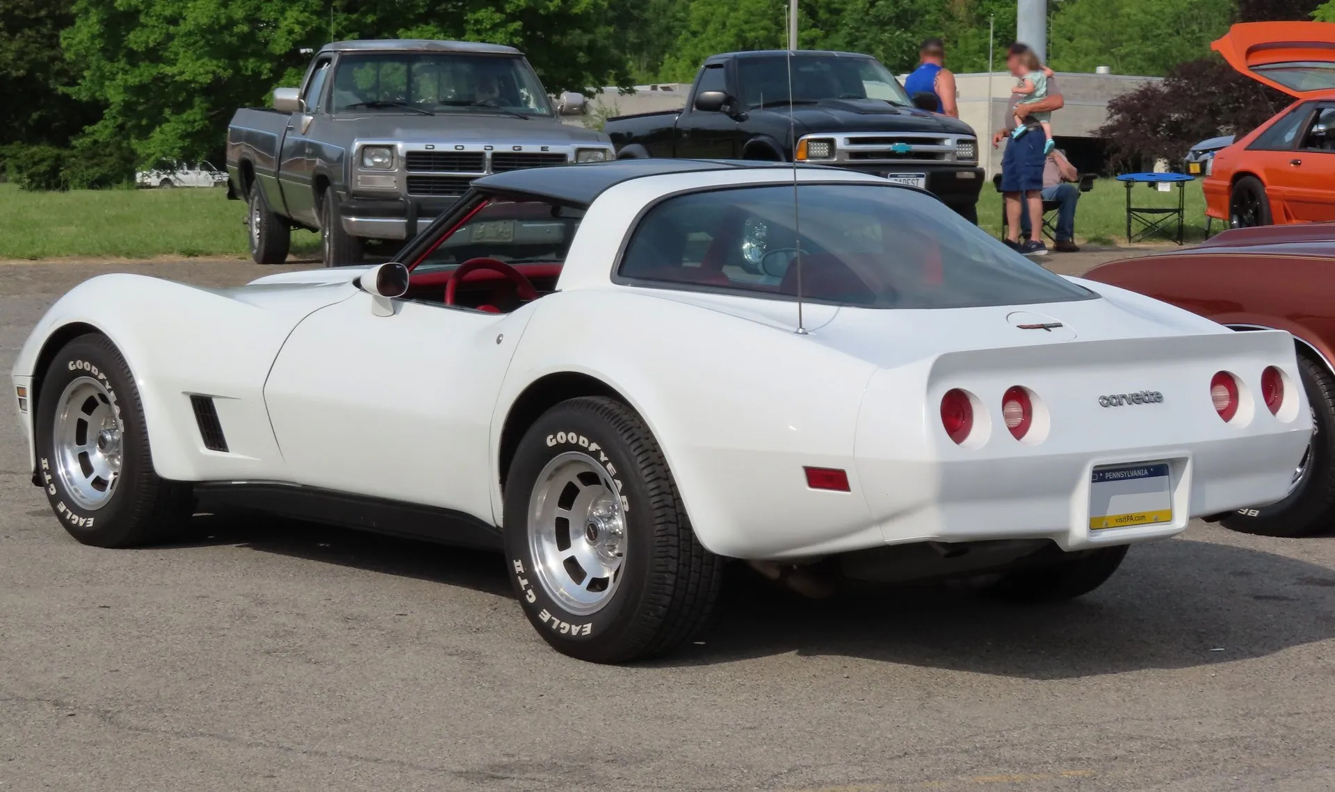 The same white Corvette coupe from the rear left, with a spoiler molded into the rear bumper cover, four round red taillights, a Corvette nameplate, the fastback rear glass and a Pennsylvania number plate.