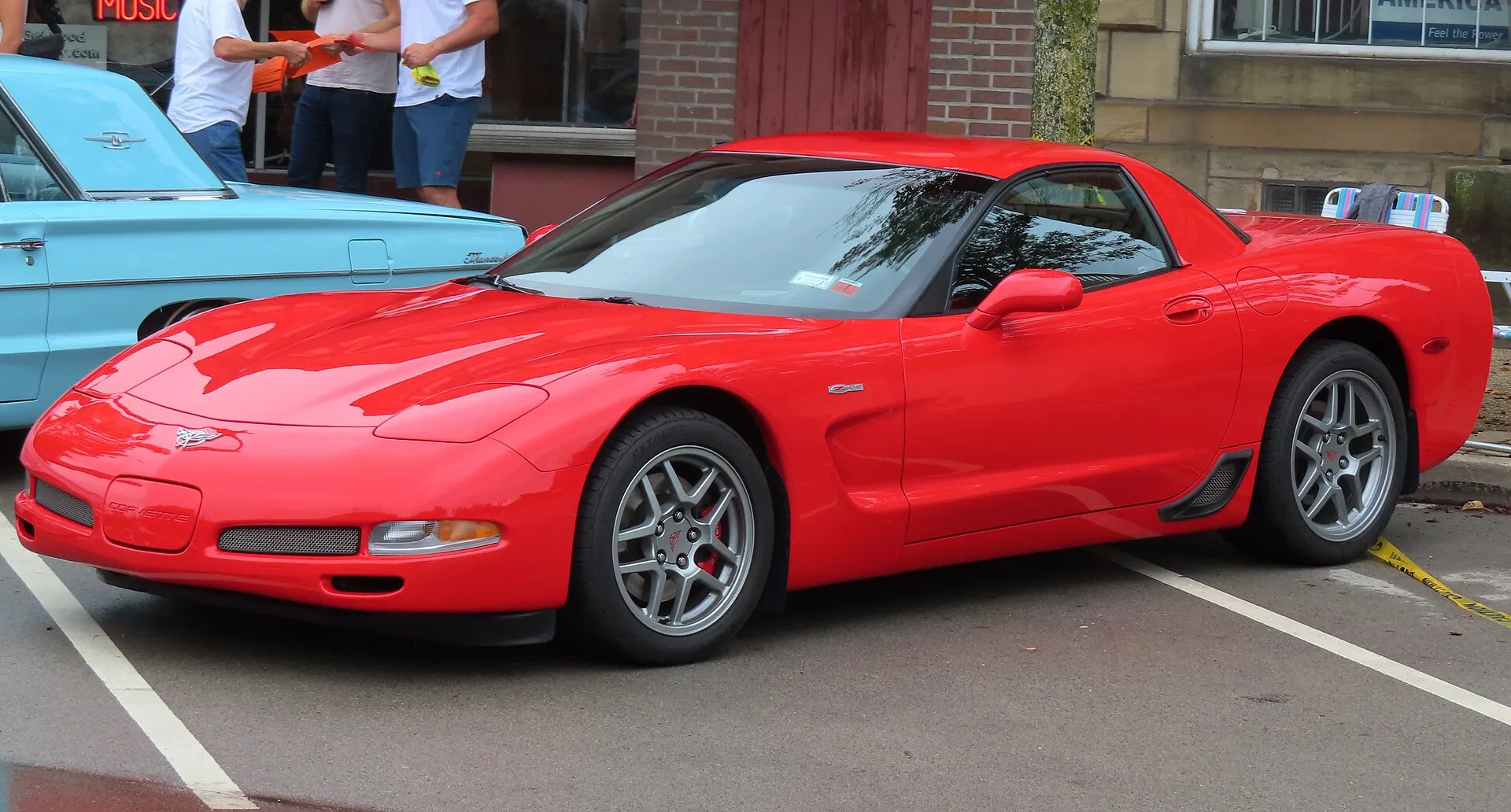 Torch Red 2003 Chevrolet Corvette Z06 parked in a street parking space, seen from the front left, with silver split five-spoke wheels, red brake calipers and a Z06 badge on the front fender.